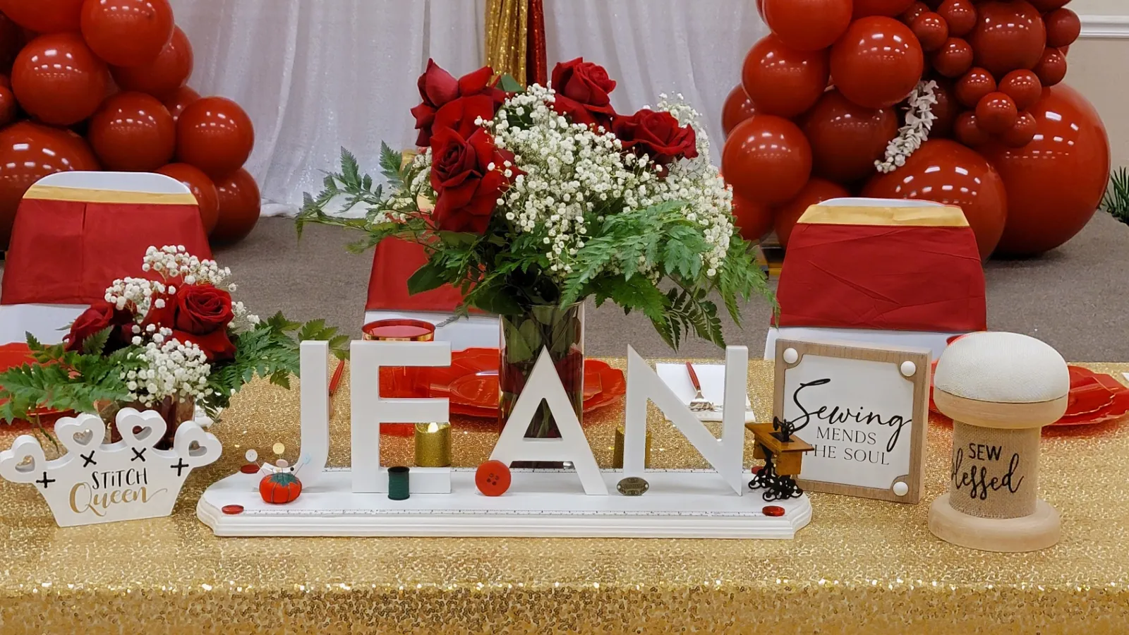 Sewing-themed head table styling with red roses, gold sequin linen and a custom name sign