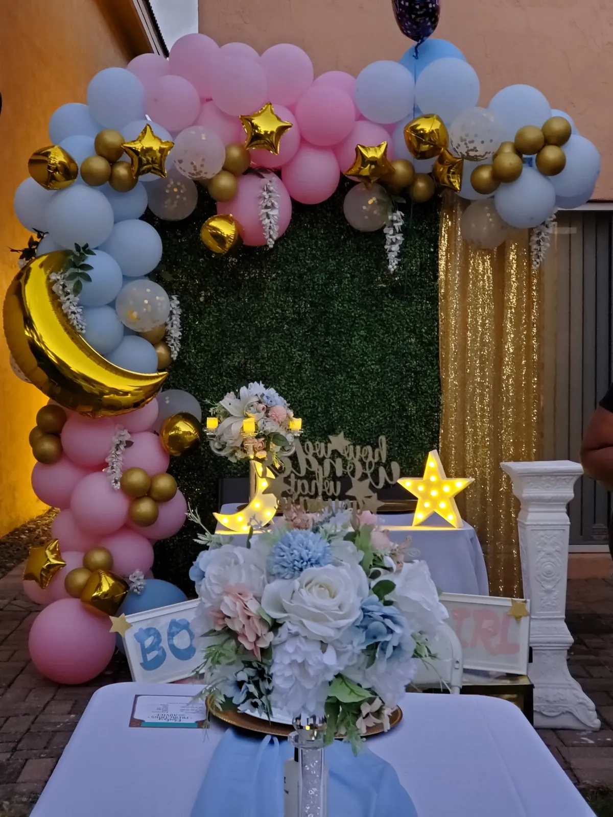Pink, blue and gold gender reveal balloon arch with greenery wall, moon and star accents at a South Florida home