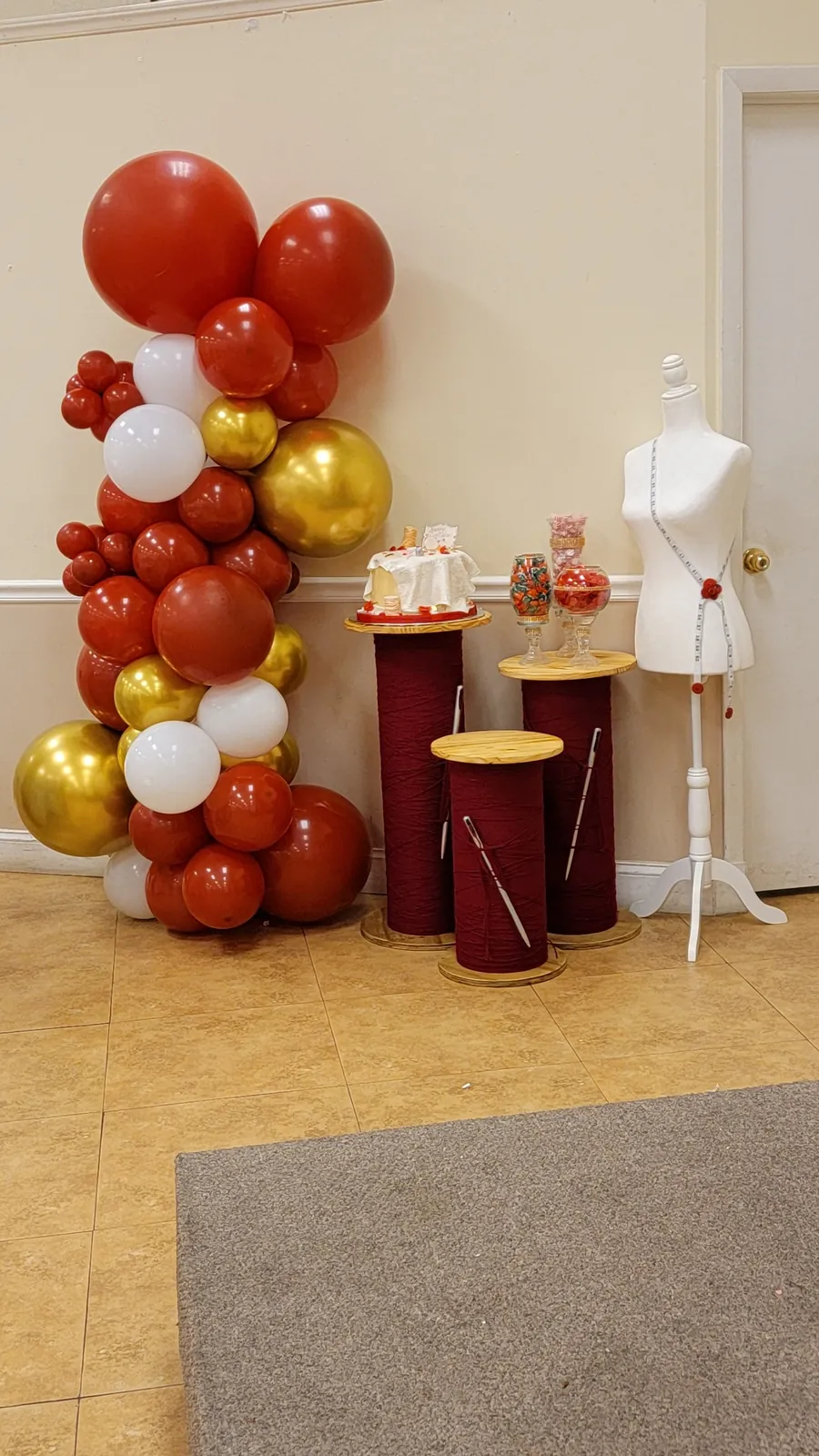 Red, gold and white balloon column with thread-spool cake pedestals and dress-form accent