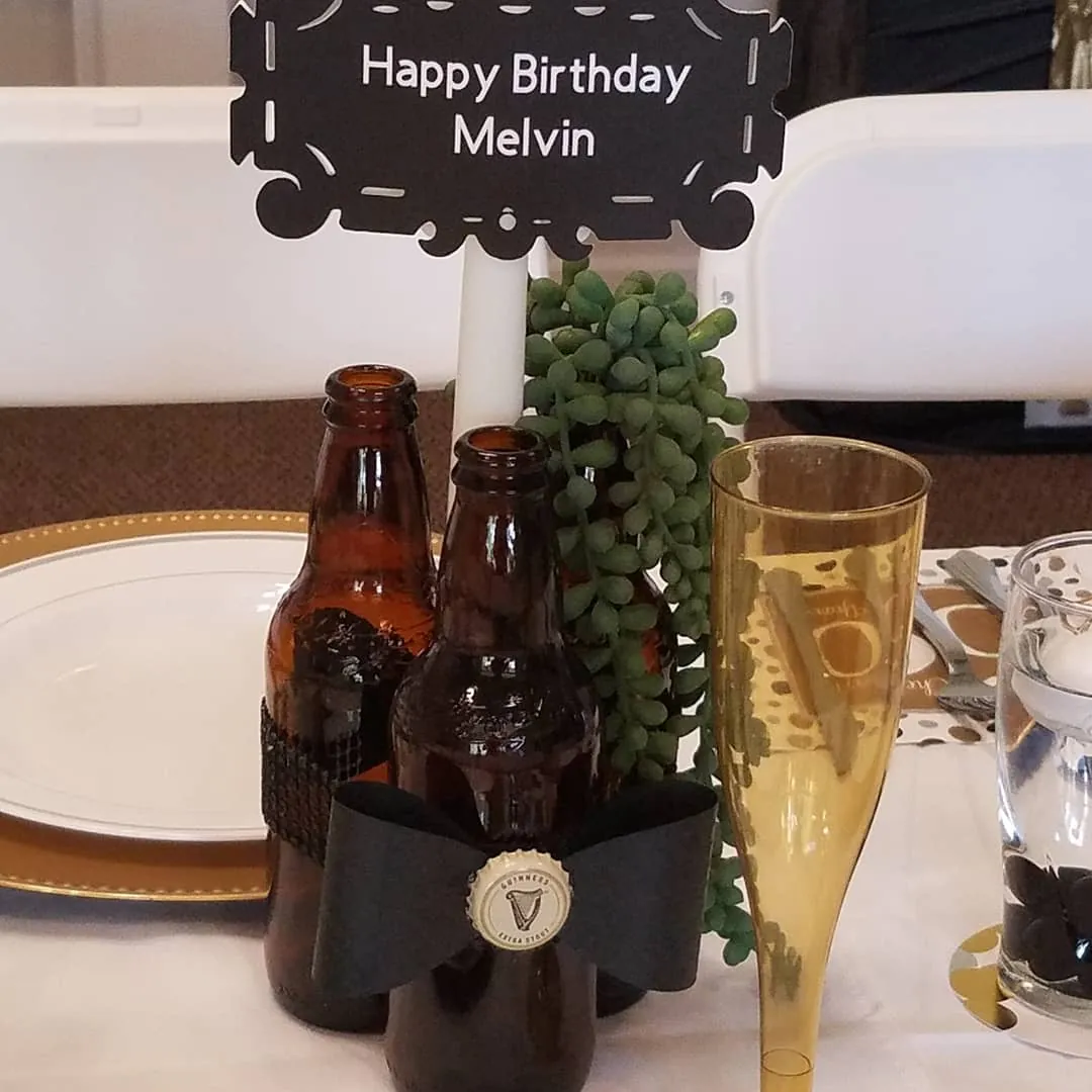Close-up centerpiece detail with bottle styling, greenery and a custom chalkboard birthday sign