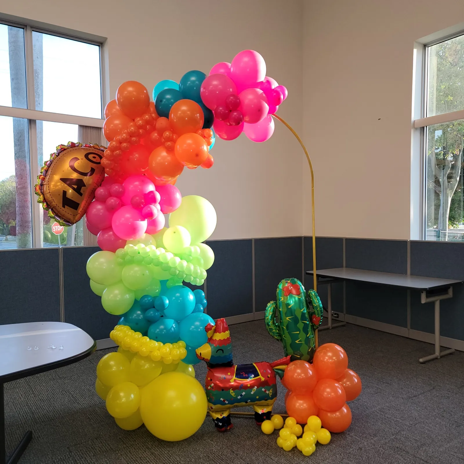 Bright fiesta-themed balloon garland with taco, piñata and cactus accents for a workplace celebration